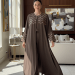 Femme portant une Abaya L'Éclat Moka élégante avec détails perlés dans un intérieur luxueux.
