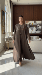 Femme portant une Abaya L'Éclat Moka élégante avec détails perlés dans un intérieur luxueux.