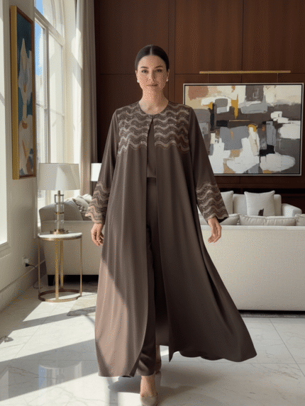 Femme portant une Abaya L'Éclat Moka élégante avec détails perlés dans un intérieur luxueux.