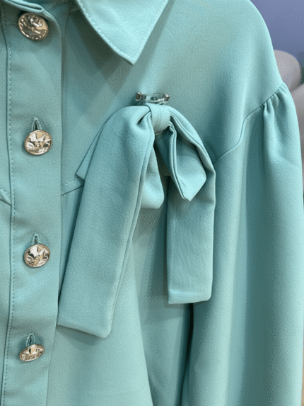 Chemisier vert menthe avec boutons dorés et nœud Orkidia Fashion.