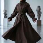 Femme portant un trench long marron élégant avec hijab, style modeste chic, Orkidia Fashion.