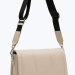 Sac bandoulière de couleur écru avec sangle large ajustable et design minimaliste porté sur fond blanc.