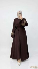 Femme portant une abaya marron élégante avec des broderies florales sur les manches, collection Orkidia Fashion.