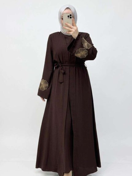 Femme portant une abaya marron élégante avec des broderies florales sur les manches, collection Orkidia Fashion.