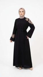 Mannequin portant une abaya noire élégante avec des broderies florales dorées sur l'épaule et les manches, collection Orkidia Fashion.