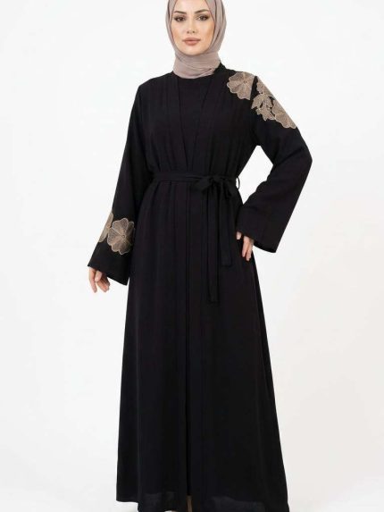 Mannequin portant une abaya noire élégante avec des broderies florales dorées sur l'épaule et les manches, collection Orkidia Fashion.