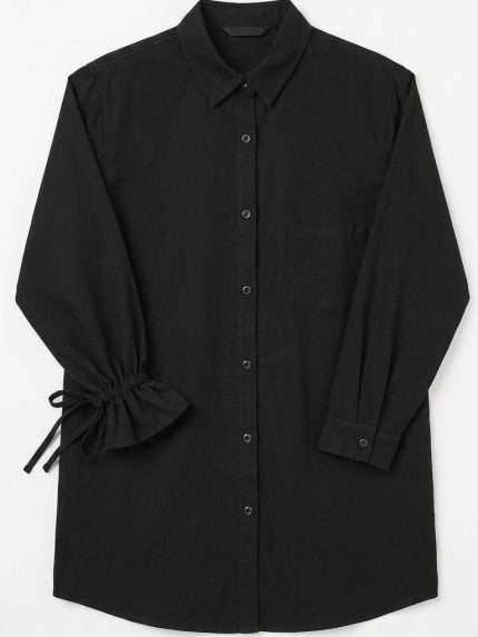 Chemise noire élégante à manches longues avec détails de volants et liens à nouer, vue de face sur fond clair.