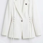Blazer blanc chic pour femme avec laçage latéral sur un fond minimaliste blanc