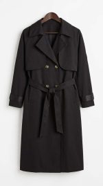 Trench-coat noir classique pour femme avec ceinture et double boutonnage sur fond blanc
