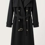 Trench-coat noir élégant pour femme avec double boutonnage et ceinture, vue de face sur fond clair.