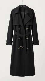 Trench-coat noir élégant pour femme avec double boutonnage et ceinture, vue de face sur fond clair.